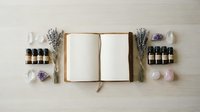Open notebook surrounded by lavender bundles, essential oil bottles and amethyst crystals on wooden surface for aromatherapy and wellness planning.