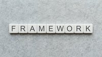Wooden letter tiles spelling FRAMEWORK on textured gray surface for business planning and organizational structure concepts.