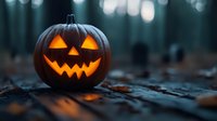 Glowing carved pumpkin with classic jack o'lantern face illuminated from within, sitting on dark forest ground with blurred bokeh lights in background at dusk.