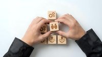 Business professional hands protecting wooden blocks with teamwork and leadership icons representing corporate strategy and employee development.