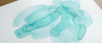 Abstract turquoise watercolor brush strokes on white paper creating organic flowing shapes for artistic backgrounds and creative design projects.