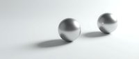 Two metallic spheres balanced on white surface creating minimalist composition with soft shadows and clean geometric forms for modern design projects.