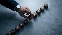 Businessman hand arranging wooden blocks with success text on concrete surface, representing business growth, planning and achievement strategy.