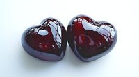 Glossy dark red glass hearts with reflective surface on white background, romantic symbol of love and passion, suitable for Valentine's Day designs and celebrations.