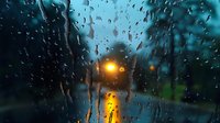 Rainy evening view through car window with street lights glowing in the distance, creating atmospheric mood during rainfall.
