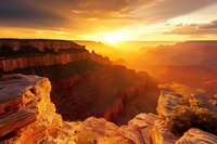 Majestic sunset over Grand Canyon with golden light illuminating red rock formations and deep valleys, creating dramatic landscape vista.