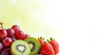 Fresh mixed fruits with red grapes, sliced kiwi and strawberries on light background for healthy eating and nutrition concepts.