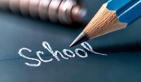Blue wooden pencil writing word School on dark chalkboard surface with chalk dust texture, macro close up view for education and learning concepts.