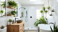 Modern spa bathroom with lush green plants, white subway tiles, wooden vanity, glass shower, and freestanding tub creating serene botanical oasis interior.