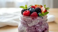 Chia seed pudding topped with fresh berries, strawberries, raspberries, and blueberries with mint leaves in a glass jar for healthy breakfast or dessert.