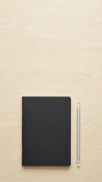 Blank black notebook and pencil on light wooden desk surface, overhead flat lay composition for stationery and office supplies design projects.