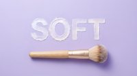 Makeup brush with wooden handle and soft bristles on lavender background with embossed soft text for beauty and cosmetics design projects.