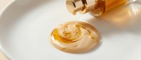 Amber liquid serum or oil swirl on white plate with bottle, skincare cosmetic product for beauty and wellness applications.