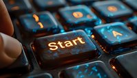 Illuminated start key on black computer keyboard with orange backlight glowing in dark environment, macro photography showing detailed texture and reflection.