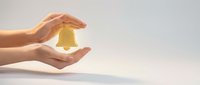 Protective hands cupping glowing golden bell symbol representing security, insurance coverage, and safety protection services for business concepts.
