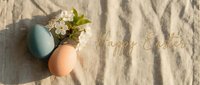 Pastel blue and pink Easter eggs with white spring blossoms on linen fabric, golden Happy Easter text, warm sunlight, holiday greeting card.