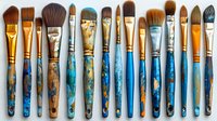 Professional makeup brushes with blue marbled handles arranged in horizontal line showing variety of brush types for cosmetic application and artistic use.