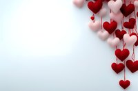 Red and pink heart decorations hanging on strings against white background for Valentine's Day celebration and romantic occasions.