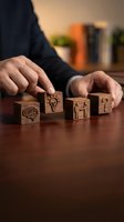 Businessman arranging wooden blocks with brain, lightbulb, teamwork and question mark symbols on desk representing business strategy and problem solving.