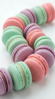 Colorful French macarons in pastel pink, green and purple arranged in rows on white background for bakery, dessert menu and confectionery design projects.