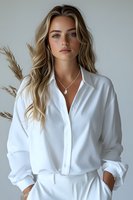 Young Caucasian woman with long blonde wavy hair wearing white button-up shirt and silver necklace, posing against light background with pampas grass decoration.