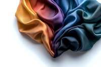 Luxurious multicolored silk fabric with elegant folds and waves creating smooth transitions between orange, purple, and blue tones on white background.