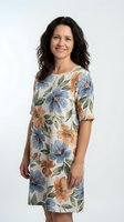 Middle-aged woman with long dark wavy hair and warm smile wearing floral print dress with blue and orange flowers on white background for fashion and lifestyle use.