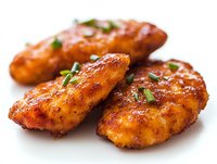 Spicy grilled chicken tenders with crispy seasoned coating and fresh herbs garnish on white background, close-up view showing juicy texture and caramelized surface.