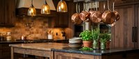 Rustic kitchen interior with copper pots hanging above a dark wood island, fresh herbs in pots, warm pendant lights, and rich wooden cabinetry.