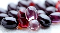 Transparent red and purple glass beads with glossy surface on white background, macro photography showing reflective surfaces and light effects.