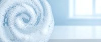 Sparkling white spiral swirl with glitter particles on soft blue and white blurred background, suitable for cosmetics, skincare, and wellness product packaging design.