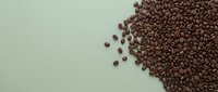 Roasted coffee beans scattered on pale green background, overhead flat lay composition for beverage, cafe, and culinary design projects.