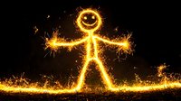 Glowing stick figure made with sparklers against dark background creates magical light painting effect, capturing motion and energy in long exposure photography.