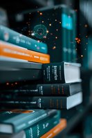 Stack of books with glowing orange particles and geometric circles floating in dark atmosphere against turquoise background, creating magical educational ambiance.