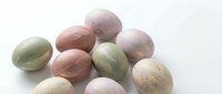 Pastel colored Easter eggs with natural marble texture scattered on white background for spring holiday decorations and seasonal crafts.