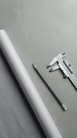 Rolled paper, pencil, and caliper on gray concrete surface, engineering and drafting tools flat lay for design and architecture concepts.