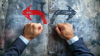 Business conflict concept showing male hands in suits drawing opposing red and blue arrows on textured concrete wall background, representing competition.