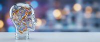 Transparent glass head with golden gears and mechanisms inside representing artificial intelligence, innovation and mental processes on blurred bokeh background.
