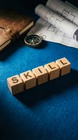 Wooden blocks spelling skill arranged on blue surface with compass, blueprints and leather journal for business training and development concepts.
