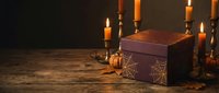 Antique wooden treasure chest with ornate metal details surrounded by glowing candles on rustic wood surface creating mysterious atmospheric lighting.