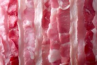 Fresh raw pork belly slices with layers of meat and fat in macro view showing marbling texture and natural pink coloring for culinary use.