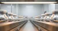 Modern commercial bakery production line with fresh bread loaves on conveyor belts in clean industrial kitchen facility for food manufacturing business.