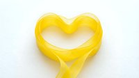 Yellow ribbon forming heart shape on white background isolated for romantic design projects and love concepts.