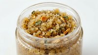 Brown sugar with spices and dried fruit pieces in open glass jar on white background, suitable for baking and cooking projects.