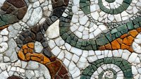 Decorative mosaic pattern with curved lines in green, orange, and white stone tiles creating abstract swirling design. Ancient Mediterranean art style.