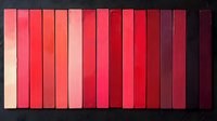 Gradient arrangement of red book spines from light to dark creating minimalist linear pattern against black background, suitable for publishing and design projects.