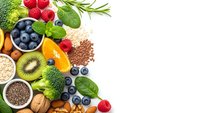 Fresh organic superfoods including berries, nuts, seeds and leafy greens arranged on white background for healthy nutrition and wellness lifestyle.