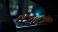 Hands typing on laptop keyboard in dark room with glowing blue digital hologram interface, representing cybersecurity and digital technology advancement.