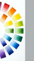 Watercolor paint swatches in rainbow spectrum from red to purple arranged in circular pattern on white paper for art supplies and creative projects.