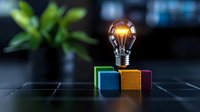 Glowing light bulb on colorful wooden blocks against dark background symbolizing creative ideas, innovation and business solutions.